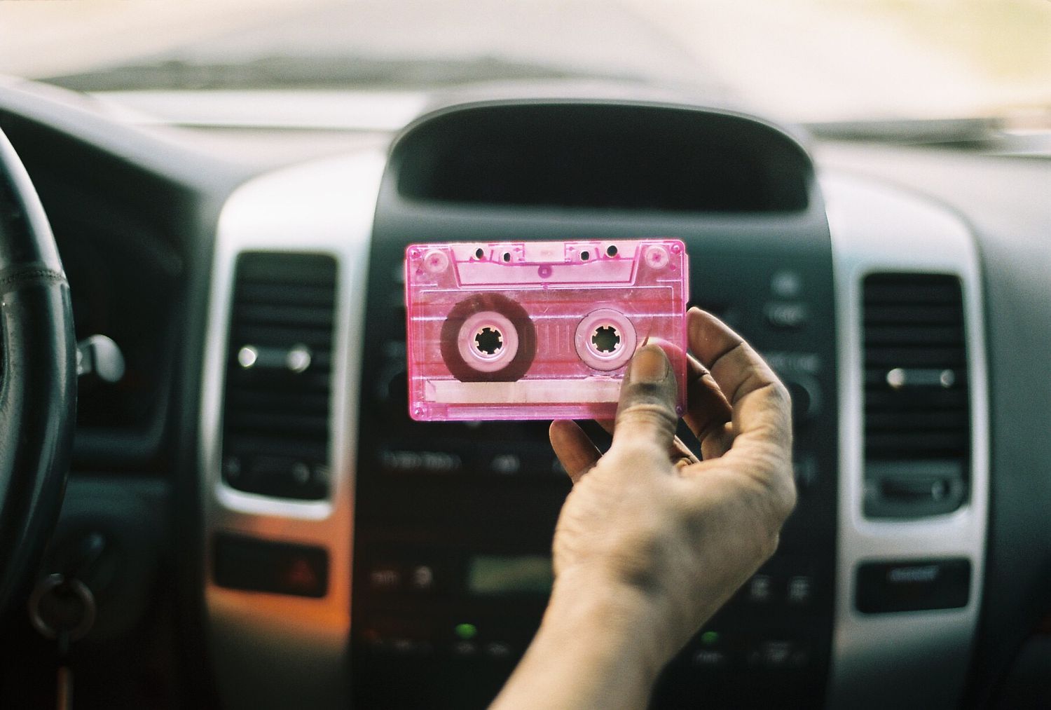 cassette tape held up in front of a car stereo system